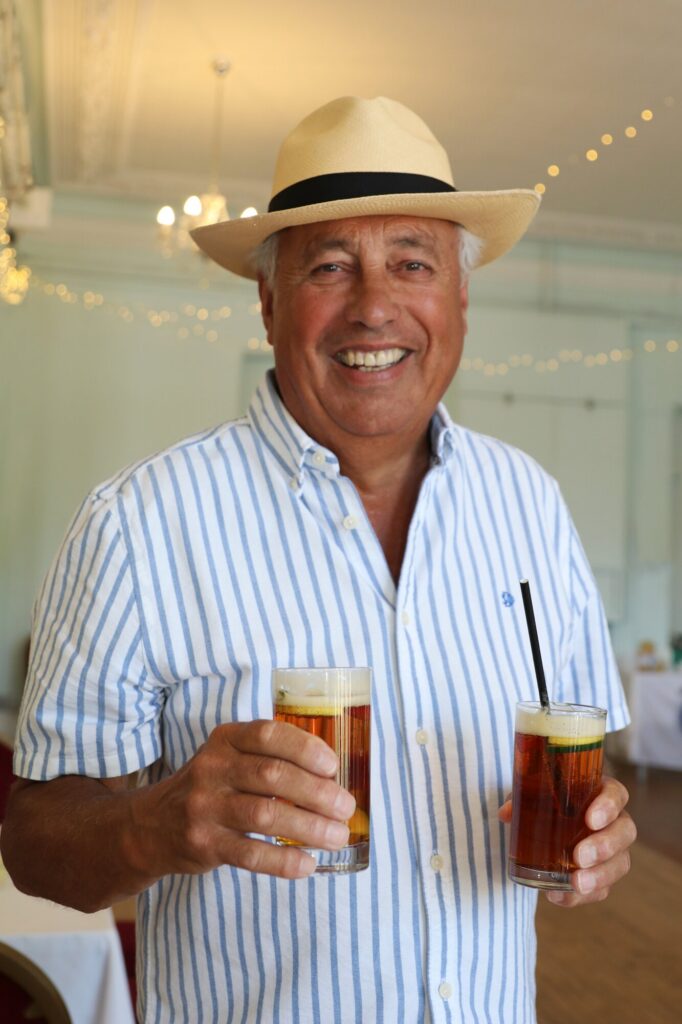 A smiling guest holding two drinks inside Cliff House