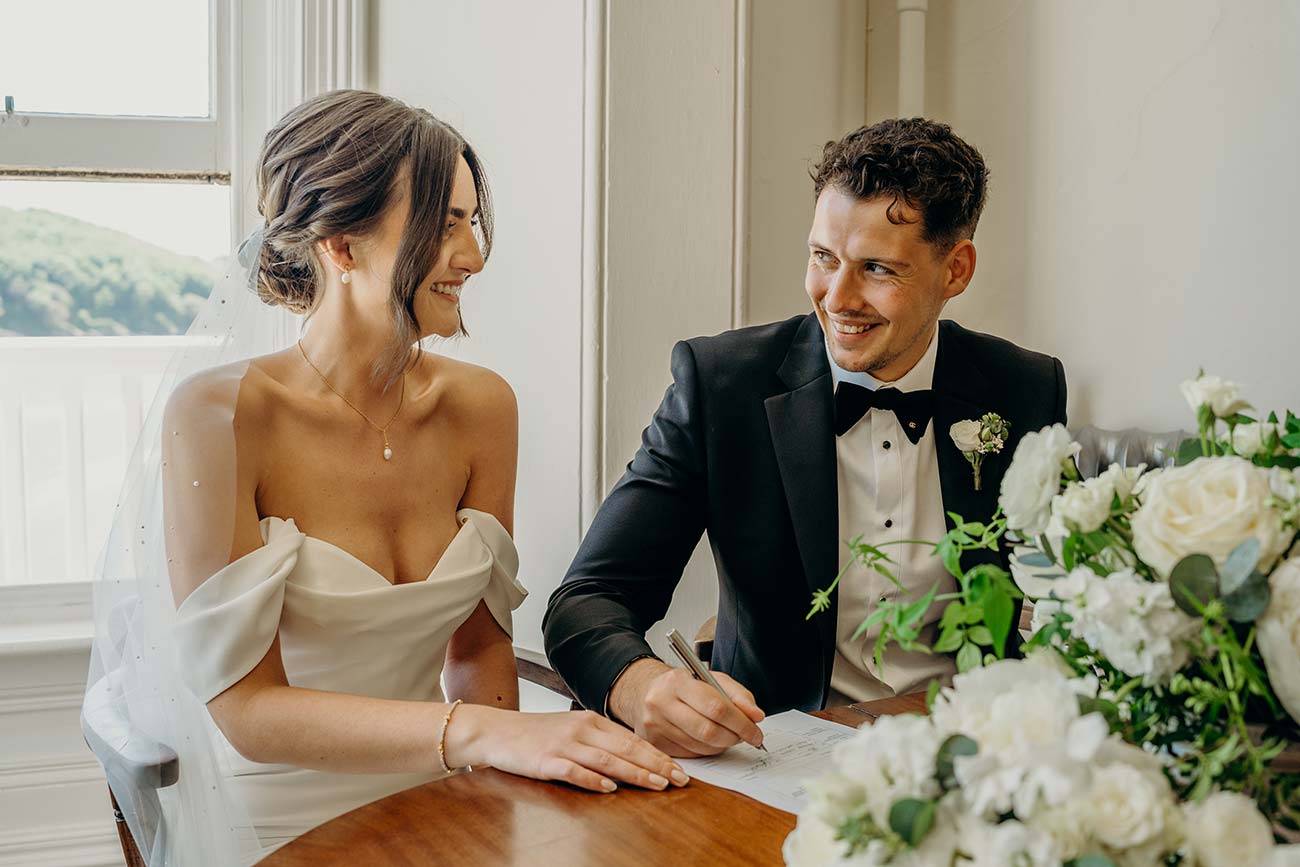 Wedding couple seated at the signing table with flowers