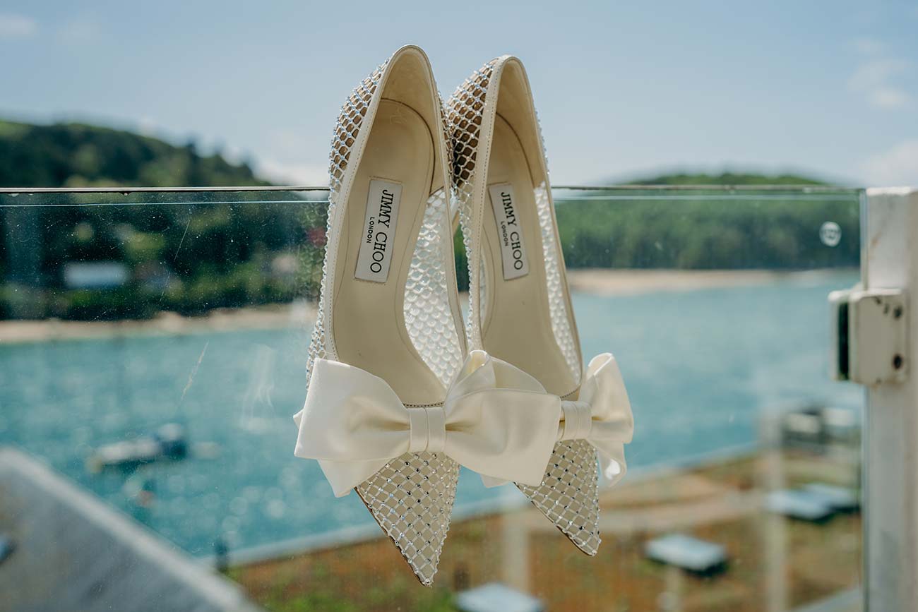 Wedding shoes beside a window overlooking the estuary